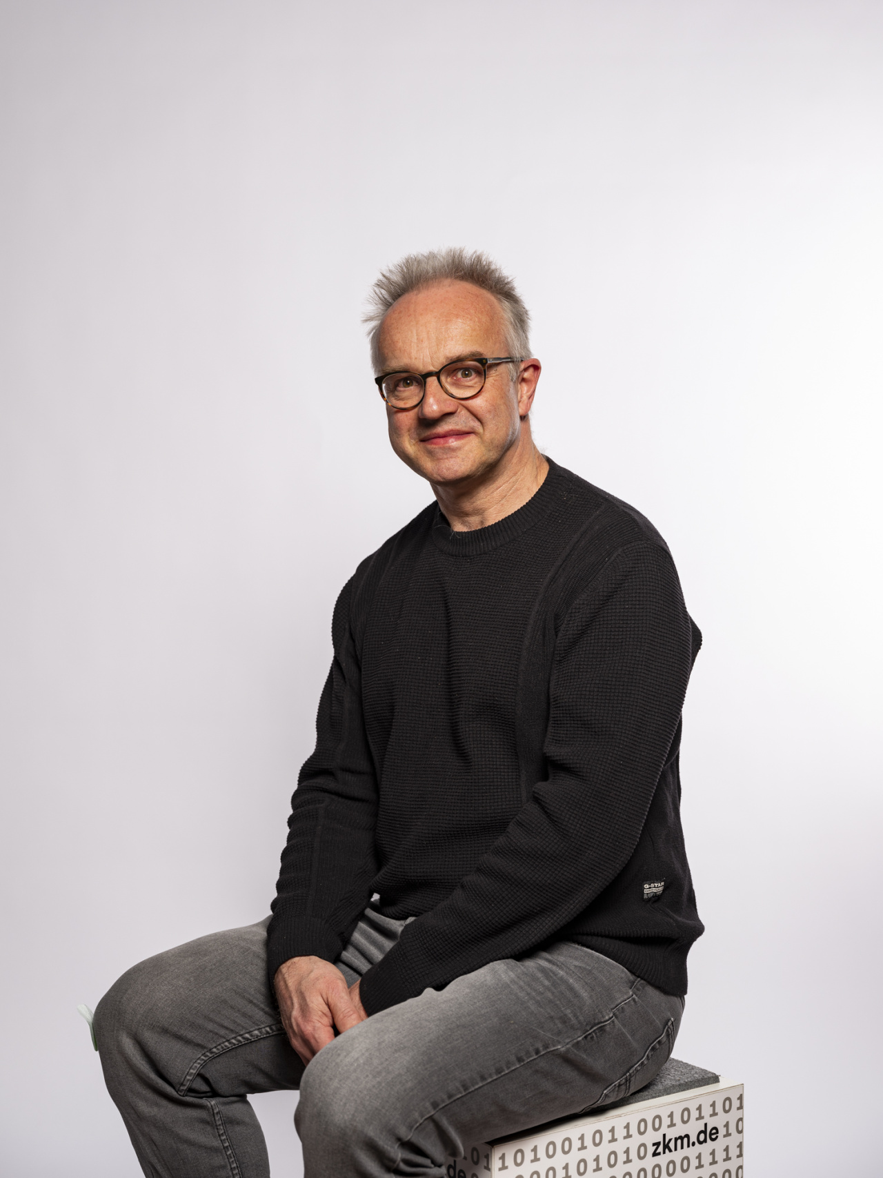sitzender mann mit Hemd und Brille