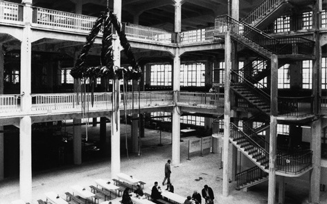 S/W Fotografie der Feierlichkeiten zum Richtfest im Hallenbau. Besucher sitzen an Bierbänken. Über ihnen der Richtkranz.